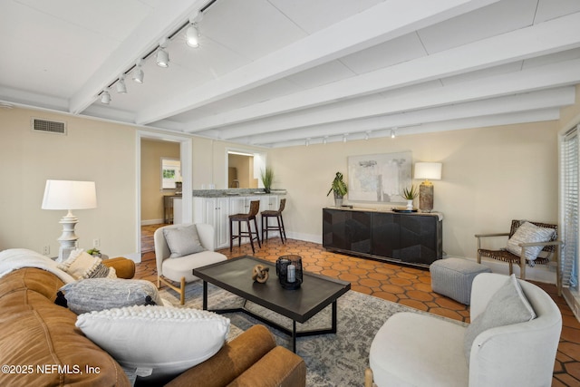 living area with track lighting, baseboards, visible vents, and beamed ceiling