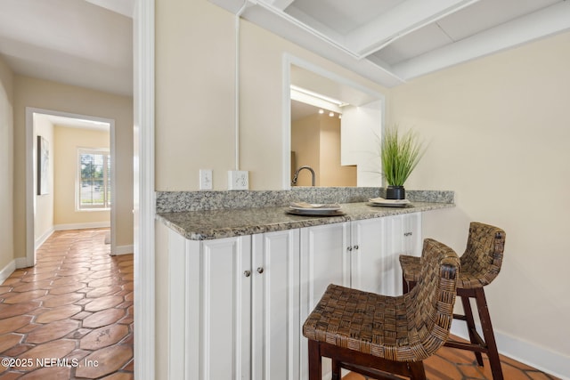 bar with baseboards, beamed ceiling, and light tile patterned flooring
