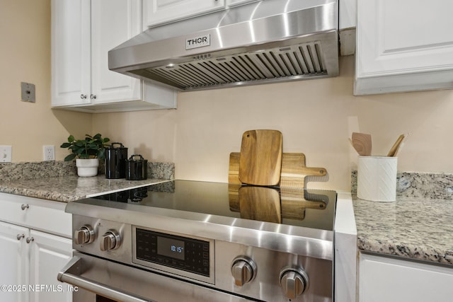 interior details with white cabinetry, under cabinet range hood, light stone countertops, and stainless steel electric range oven