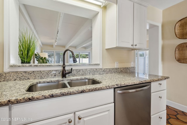 kitchen featuring stainless steel dishwasher, white cabinets, light stone countertops, and a sink