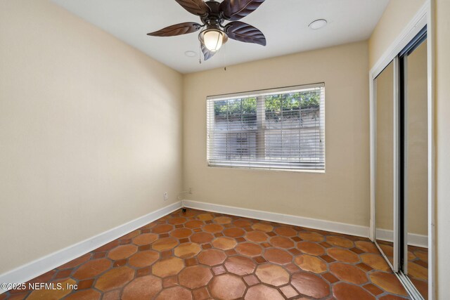 unfurnished bedroom featuring baseboards, a ceiling fan, and a closet