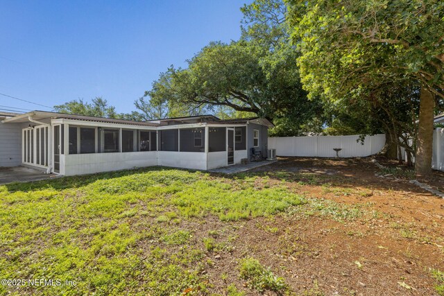 rear view of property with a yard, a sunroom, and fence private yard