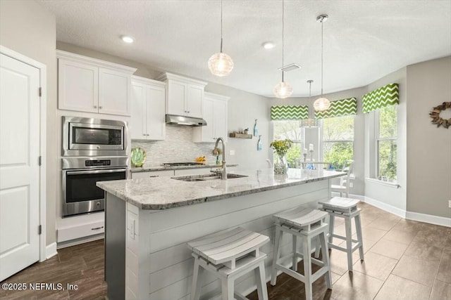 489 Citrus Ridge Dr, Ponte Vedra, FL 32081 - kitchen with tasteful backsplash, light stone counters, under cabinet range hood, visible vents, and a sink