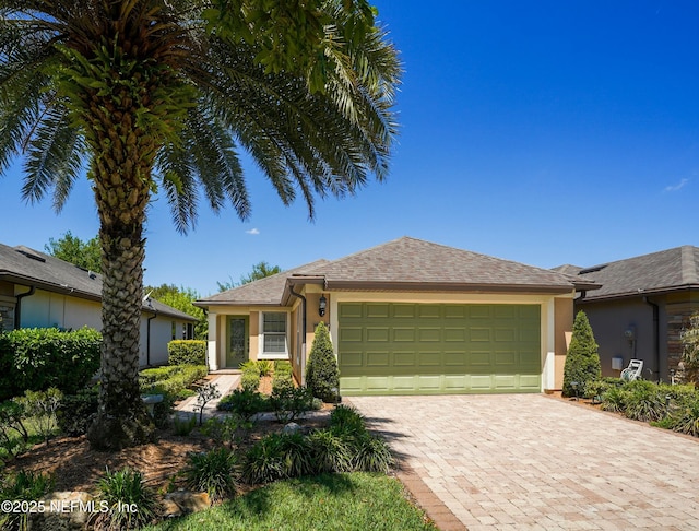 single story home featuring a shingled roof, a garage, stucco siding, and driveway