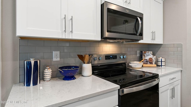 173 Greenwood Dr, Palm Coast, FL 32137 - kitchen featuring stainless steel microwave, white cabinetry, light stone counters, and electric range oven
