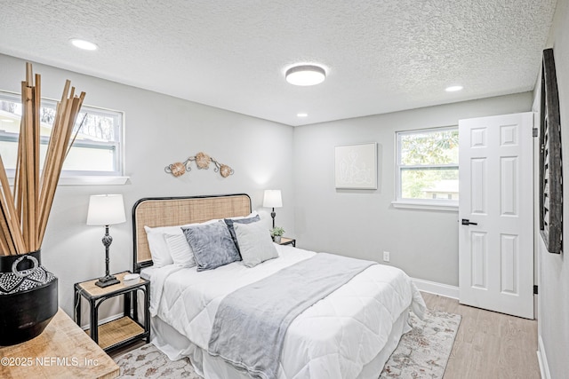 310 Capella Rd, Orange Park, FL 32073 - bedroom with light wood-style floors, baseboards, multiple windows, and a textured ceiling