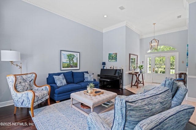 living room with baseboards, wood finished floors, a chandelier, and crown molding