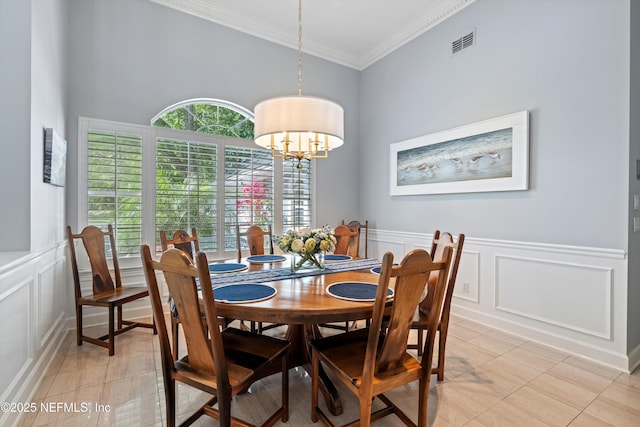 dining room featuring a decorative wall, crown molding, light tile patterned flooring, an inviting chandelier, and visible vents