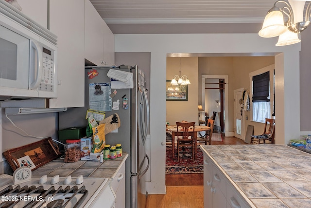 627 Emmett St, Palatka, FL 32177 - kitchen with white microwave, white cabinetry, tile countertops, and an inviting chandelier