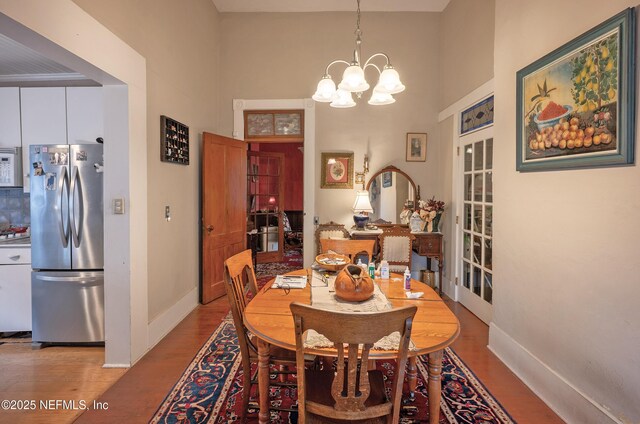 627 Emmett St, Palatka, FL 32177 - dining area with baseboards, a notable chandelier, wood finished floors, and a high ceiling