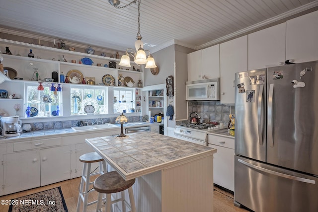 627 Emmett St, Palatka, FL 32177 - kitchen featuring tile countertops, white cabinetry, ornamental molding, appliances with stainless steel finishes, and a sink