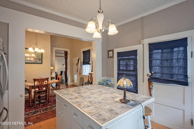 627 Emmett St, Palatka, FL 32177 - kitchen featuring pendant lighting, light wood-style floors, an inviting chandelier, ornamental molding, and tile counters