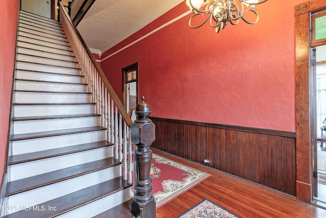 627 Emmett St, Palatka, FL 32177 - stairway with a notable chandelier, crown molding, wainscoting, wood finished floors, and wood walls