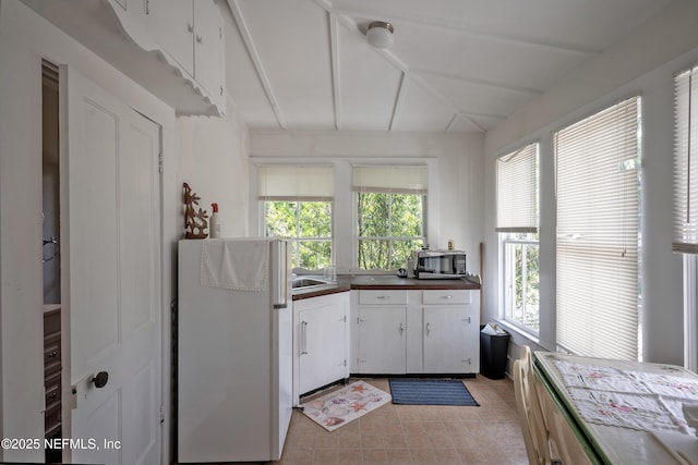 627 Emmett St, Palatka, FL 32177 - kitchen with plenty of natural light, light tile patterned floors, white cabinetry, and freestanding refrigerator