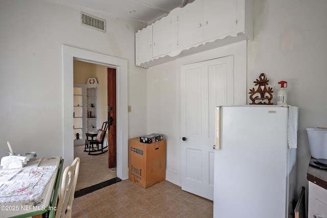 627 Emmett St, Palatka, FL 32177 - kitchen with visible vents, white cabinets, freestanding refrigerator, and light colored carpet
