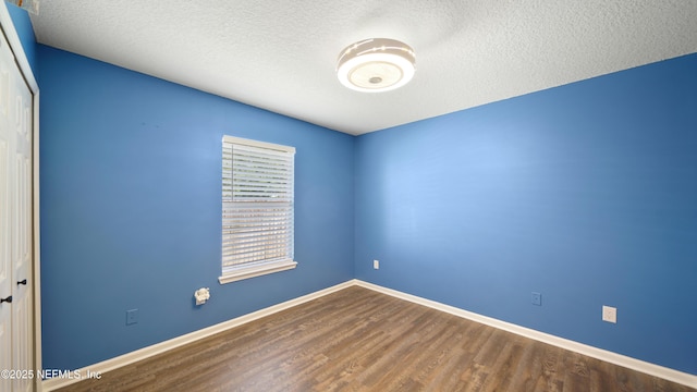 empty room with baseboards, wood finished floors, and a textured ceiling