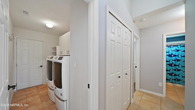 laundry room with washer and clothes dryer, cabinet space, a textured ceiling, and light tile patterned flooring