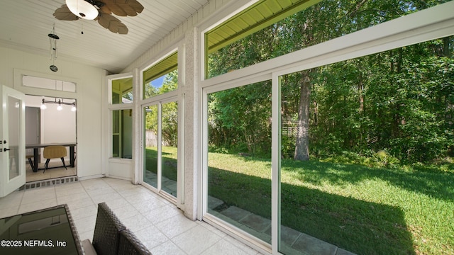 unfurnished sunroom featuring ceiling fan and tile patterned flooring