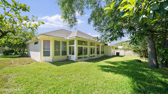 back of property featuring a yard, a sunroom, fence, and roof with shingles
