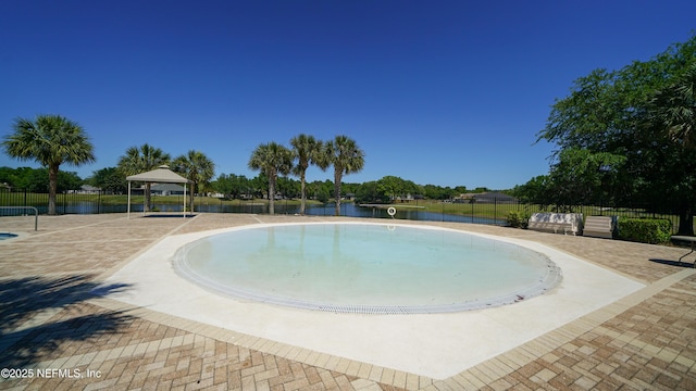 view of swimming pool with fence, a water view, and a gazebo