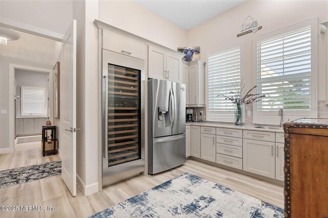 8 Island Estates Pkwy, Palm Coast, FL 32137 - kitchen with baseboards, stainless steel refrigerator with ice dispenser, a sink, light wood-style flooring, and beverage cooler