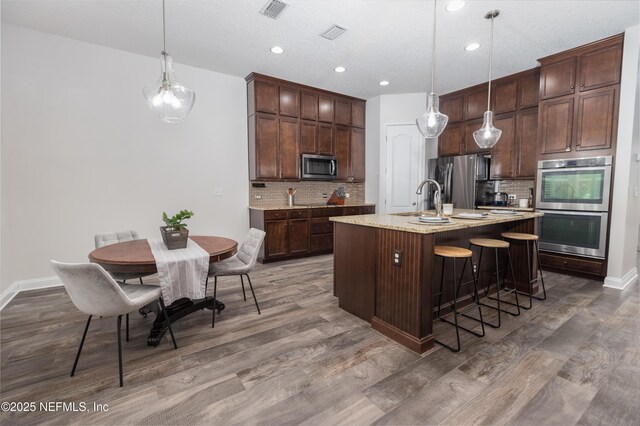 184 Rockcreek Dr, Saint Johns, FL 32259 - kitchen with stainless steel appliances, wood finished floors, decorative backsplash, a kitchen breakfast bar, and recessed lighting