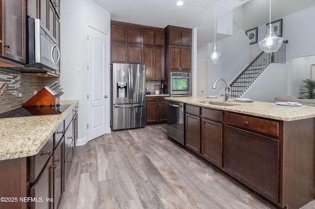 184 Rockcreek Dr, Saint Johns, FL 32259 - kitchen featuring appliances with stainless steel finishes, a sink, light wood-type flooring, tasteful backsplash, and dark brown cabinetry