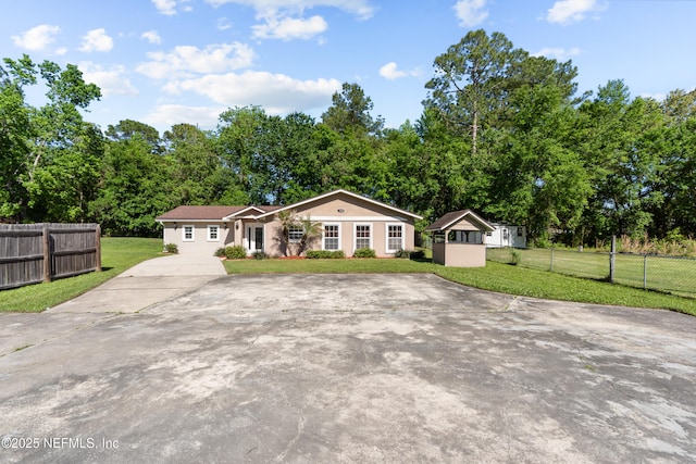 view of front of property featuring driveway, fence, and a front lawn