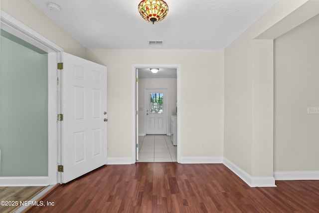entrance foyer with washing machine and dryer, visible vents, baseboards, and wood finished floors