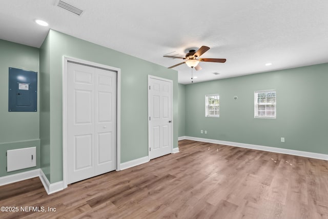 unfurnished bedroom with visible vents, baseboards, electric panel, recessed lighting, and wood finished floors