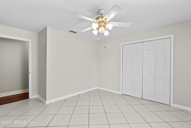 unfurnished bedroom with a closet, light tile patterned floors, baseboards, and visible vents