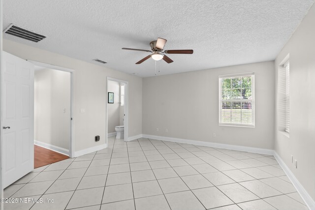 unfurnished room featuring baseboards, visible vents, a textured ceiling, and a ceiling fan