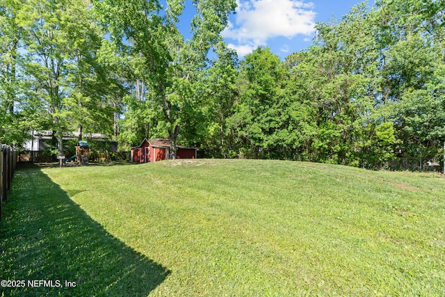 view of yard featuring a shed, fence, and an outdoor structure