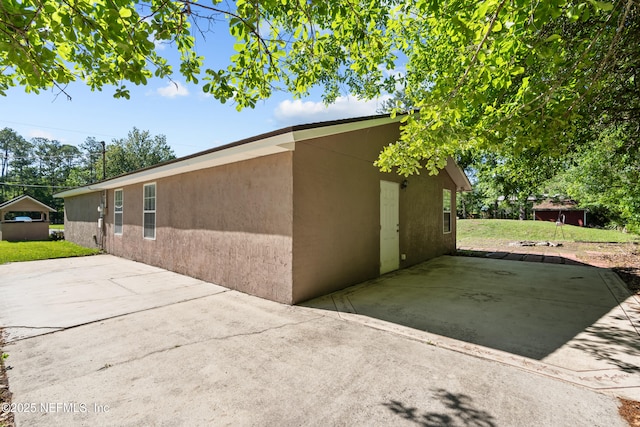 view of side of property featuring a patio, a lawn, and stucco siding