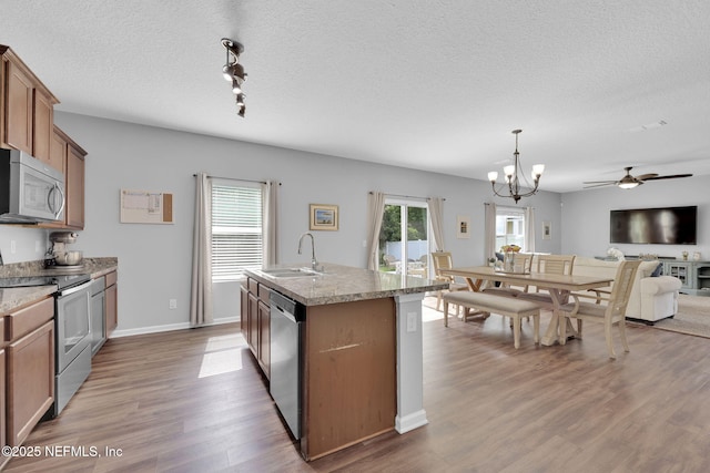 3699 Summit Oaks Dr, Green Cove Springs, FL 32043 - kitchen with open floor plan, brown cabinets, stainless steel appliances, a sink, and wood finished floors
