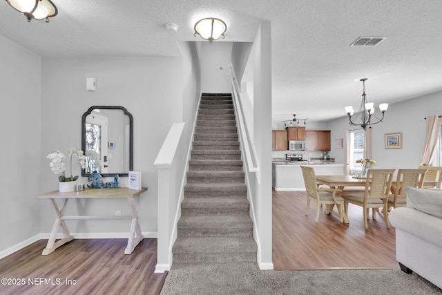 3699 Summit Oaks Dr, Green Cove Springs, FL 32043 - stairs featuring visible vents, baseboards, a notable chandelier, a textured ceiling, and wood finished floors