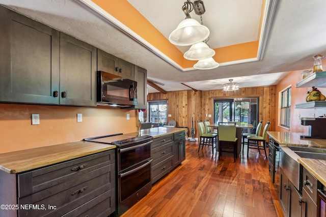 5822 Silver Sands Cir, Keystone Heights, FL 32656 - kitchen with wooden walls, range with two ovens, hardwood / wood-style flooring, and black microwave