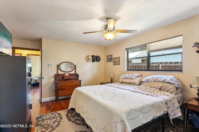 5822 Silver Sands Cir, Keystone Heights, FL 32656 - bedroom with freestanding refrigerator, baseboards, a ceiling fan, and wood finished floors