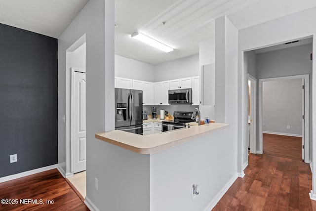 8601 Beach Blvd Unit 905, Jacksonville, FL 32216 - kitchen featuring wood finished floors, light countertops, white cabinets, a peninsula, and appliances with stainless steel finishes