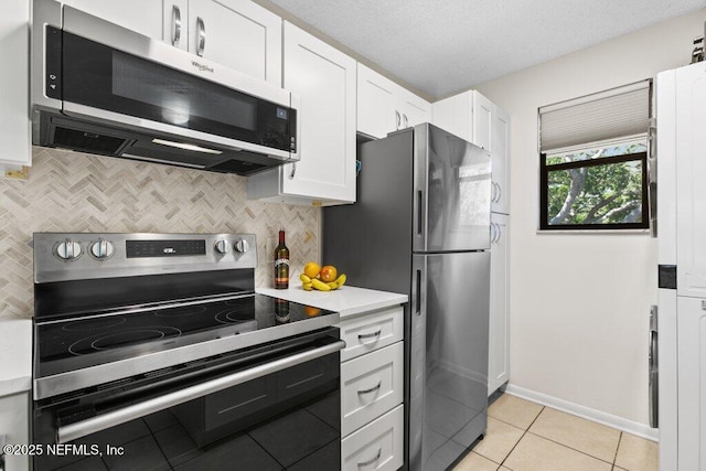 kitchen with tasteful backsplash, light tile patterned floors, light countertops, appliances with stainless steel finishes, and white cabinetry