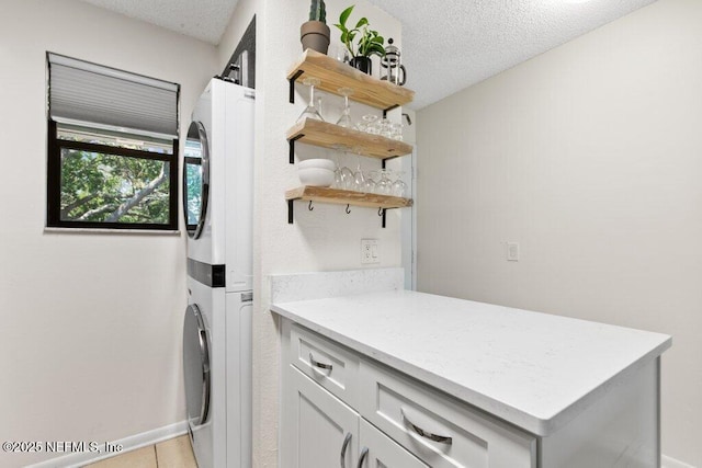 laundry room with cabinet space, stacked washing maching and dryer, and a textured ceiling