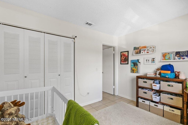 tiled bedroom with baseboards, a closet, a crib, a textured ceiling, and visible vents