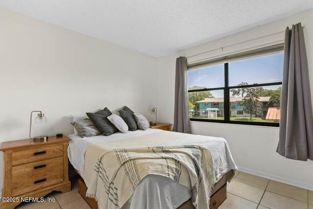 bedroom with a textured ceiling, baseboards, and light tile patterned flooring
