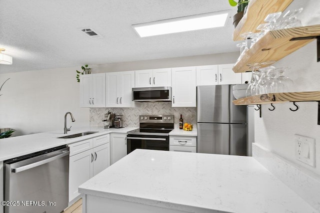 kitchen featuring a peninsula, a sink, visible vents, and stainless steel appliances