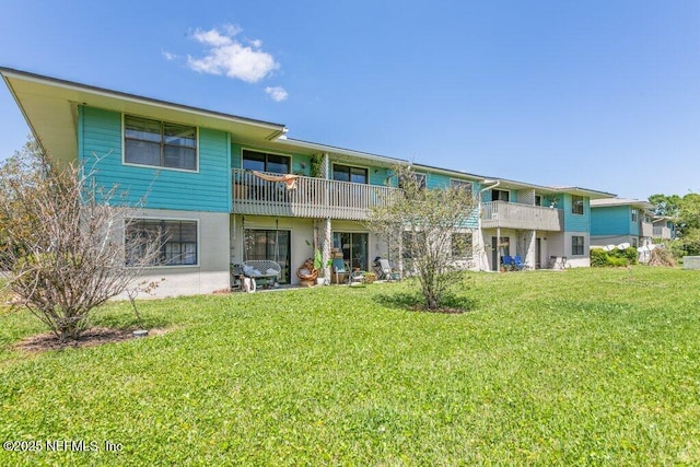 back of property with a balcony and a lawn