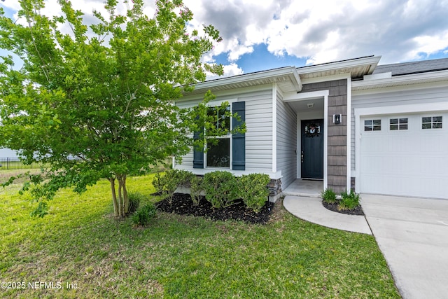 view of exterior entry featuring a garage and a lawn