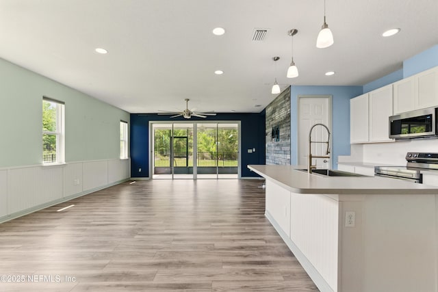 kitchen featuring visible vents, a sink, stainless steel appliances, open floor plan, and plenty of natural light