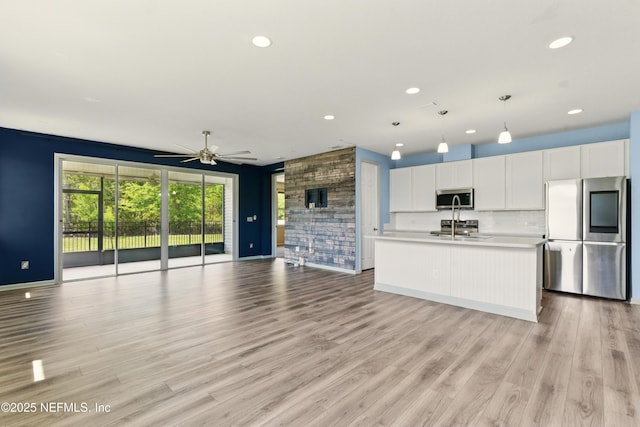 kitchen featuring light wood-style flooring, white cabinets, appliances with stainless steel finishes, light countertops, and open floor plan