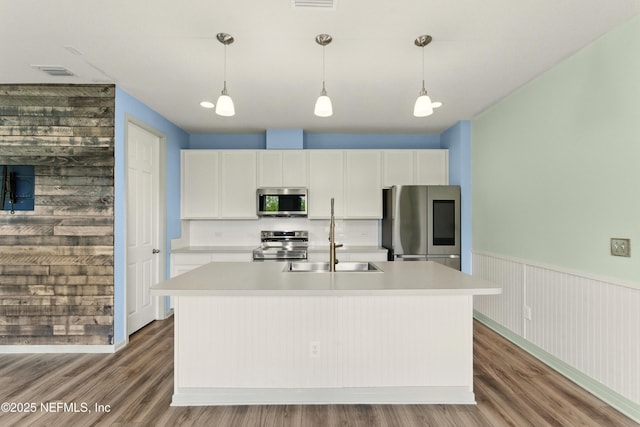 kitchen with an island with sink, visible vents, light countertops, stainless steel appliances, and decorative light fixtures