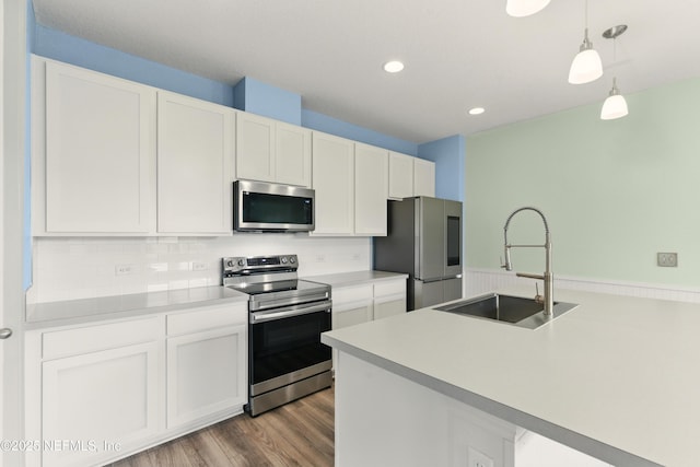 kitchen featuring white cabinetry, backsplash, decorative light fixtures, stainless steel appliances, and a sink